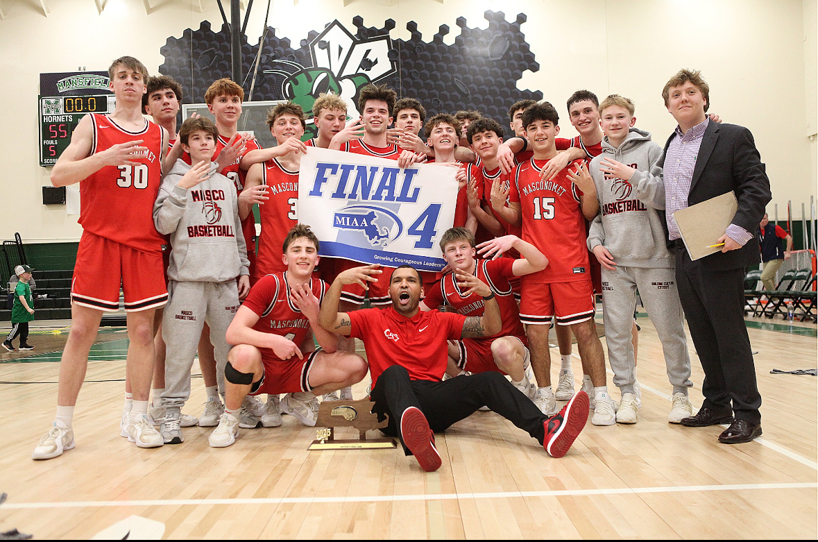 Masco taking a picture with the final four banner with coach Jaycob Morales infront. 